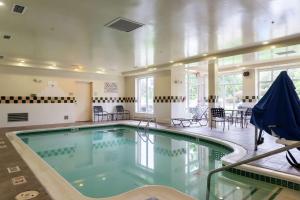 - une piscine dans un bâtiment avec des chaises et des tables dans l'établissement Hilton Garden Inn Plymouth, à Plymouth