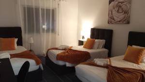 una camera d'albergo con tre letti con lenzuola arancioni di Areal de Santa Bárbara Sea View a Ribeira Grande