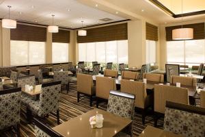 a restaurant with tables and chairs and windows at Hilton Garden Inn DFW Airport South in Irving
