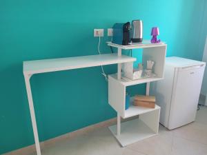 einen weißen Schreibtisch mit einem Regal neben einer blauen Wand in der Unterkunft Kalimera in Bari