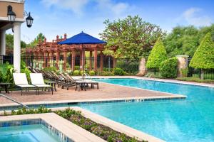 a swimming pool with chairs and an umbrella at Hilton Dallas Southlake Town Square in Southlake