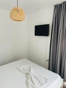 a bedroom with a white bed and a light fixture at Daro tiny house in Vama Veche