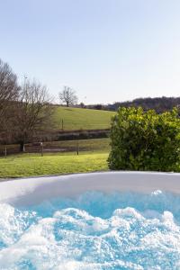 a bath tub filled with blue water in a field at The Retreat, Sauna & Hot Tub, Charming & Cosy Gem in Blandford Forum