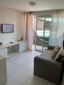 uma sala de estar com um sofá, uma mesa e uma janela em Flat na Orla de Tambaú em João Pessoa