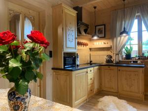 a kitchen with a vase with red roses in it at Siumno Chatka domki z ruską balią in Murzasichle