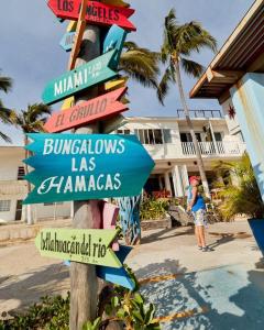 un cartello stradale con molti cartelli su un palo di Bungalows Las Hamacas a San Patricio Melaque
