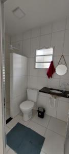 a bathroom with a toilet and a sink and a window at Pousada Aconchego Ocian in Praia Grande
