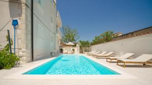 a swimming pool with lounge chairs and a house at Villa Bianca Vodice in Vodice
