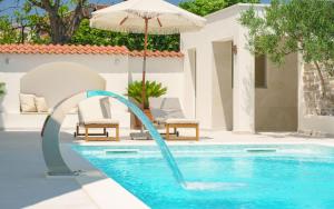 a pool with an umbrella and a water slide at Villa Bianca Vodice in Vodice