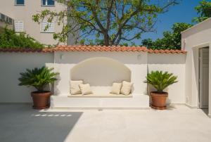 a white bench on a wall with two plants at Villa Bianca Vodice in Vodice