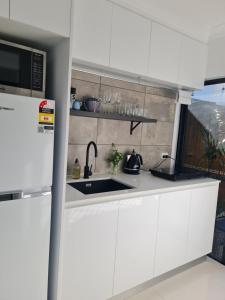 a kitchen with white cabinets and a sink at Blue Lagoon Tropical Sanctuary in Trinity Beach