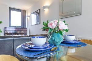 una mesa con dos tazas y platos y un jarrón de flores en Lovely & Cosy 2 Beds London skyline view en Londres