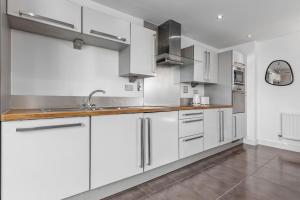 una cocina con armarios blancos y electrodomésticos de acero inoxidable en Lovely & Cosy 2 Beds London skyline view en Londres