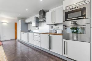 una cocina con armarios blancos y electrodomésticos de acero inoxidable en Lovely & Cosy 2 Beds London skyline view en Londres