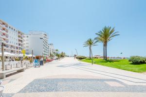 クアルテイラにあるApartamento T1 praiaのヤシの木や建物が立ち並ぶ海岸の散歩道