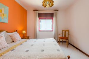 クアルテイラにあるApartamento T1 praiaのベッドルーム1室(オレンジ色の壁の大型ベッド1台付)