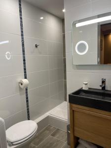 een badkamer met een toilet, een wastafel en een spiegel bij Cit'Hôtel le Welcome in Moutiers