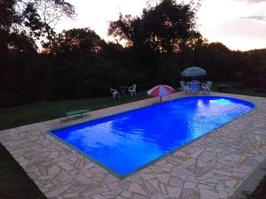 una piscina azul con sillas y sombrilla en Chacara Vale dos Sonhos Itu, en Itu