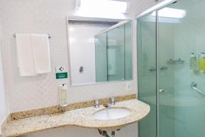 uma casa de banho com um lavatório e uma cabina de duche em vidro. em Eldorado Atibaia Eco Resort em Atibaia