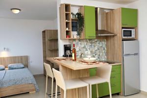 a small kitchen with green cabinets and a table with chairs at Apartments Oktopus in Sutomore