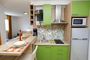 cocina con armarios verdes y nevera blanca en Apartments Oktopus, en Sutomore