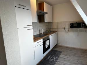 een keuken met witte kasten en een wastafel bij A&V Apartments Schöne Dachgeschoss Wohnung in Gelsenkirchen