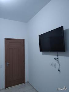 Habitación con puerta y TV de pantalla plana en la pared. en POUSADA ROSA DOS LENÇÓIS, en Barreirinhas