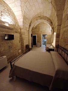 a bedroom with a large bed in a stone room at Tenuta Pigliano Dependance in Bagnolo del Salento