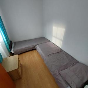 ein kleines Schlafzimmer mit einem Bett und einem Holzboden in der Unterkunft Szary domek 1 in Wieprz