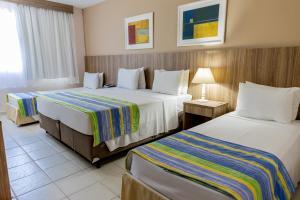 Eldorado Atibaia Eco Resort في أتيبايا: غرفه فندقيه سريرين ومصباح