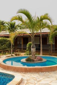 a pool with palm trees in front of a building at Portal Da Mata in Santa Fé do Sul