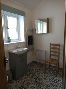 y baño con lavabo, silla y espejo. en Vineyard Barns Gower, en Swansea