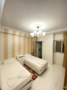 1 dormitorio con 2 camas y lámpara de araña en Centre ville appartement en Alhucemas
