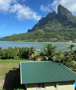 ein Haus mit einem grünen Dach neben einem Berg in der Unterkunft Bora Temahana in Bora Bora