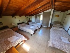 3 camas en una habitación con techos de madera en El Refugio De Posta en Santa Rosa de Calamuchita