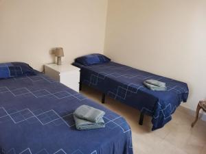 twee bedden in een kamer met blauwe lakens en handdoeken bij Belrodagolf in San Javier