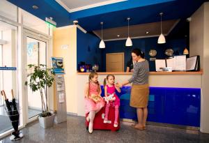 Eine Frau und zwei kleine Mädchen stehen in einem Zimmer in der Unterkunft Krasnodar Aerohotel in Krasnodar