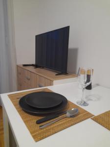 a table with a black plate and a tv at Nikola NS in Novi Sad