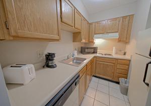 uma cozinha com armários de madeira, um lavatório e um micro-ondas em All Season Suites em Pigeon Forge