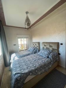 - une chambre avec 2 lits et des couettes bleues dans l'établissement Eden Appartement avec Piscine Et Salle de Sport, à El Jadida
