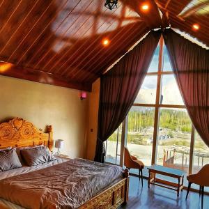 a bedroom with a bed and a large window at Oasis Resort in Skardu