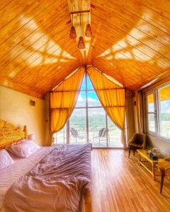 a bedroom with a large wooden ceiling with a large window at Oasis Resort in Skardu