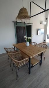 een houten tafel met stoelen en een vaas met bloemen erop bij La Casa de Abajo in Arroyomolinos de la Vera