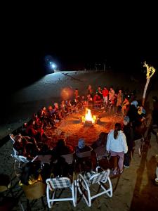 a group of people sitting around a fire on the beach at Oasis Resort in Skardu