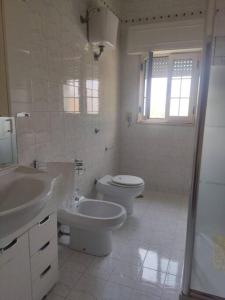 Baño blanco con 2 aseos y lavamanos en A un passo dal cuore, en Mesagne 8 fotos más