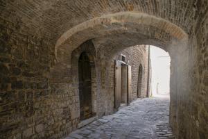 an alley in a brick wall with an archway at Monolocale centro storico in Gubbio