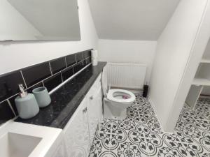 uma casa de banho com WC e piso em azulejo preto e branco em Sigma Palace em Longbenton
