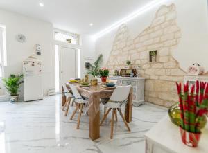 a kitchen with a table with chairs and a stone wall at Casa N'Amuri Scicli in Scicli