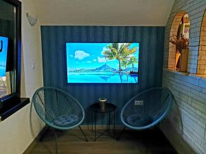 two chairs in a room with a tv on a wall at Natural Cottage Una in Bihać