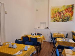 a restaurant with yellow tables and chairs and a painting on the wall at Beverley Dean - Children Over 5 Years Welcome - Continental Breakfast in Blackpool